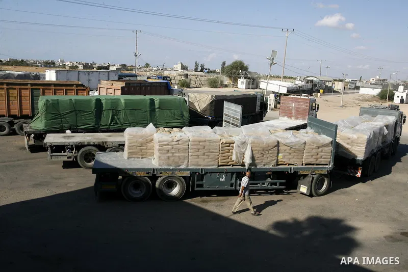 An employee walks past trucks loaded with bags of cement entering the Gaza Strip from Israel through the Kerem Shalom crossing, in Rafah in southern Gaza on October 14, 2014. International donors pledged about $5.4 billi...
