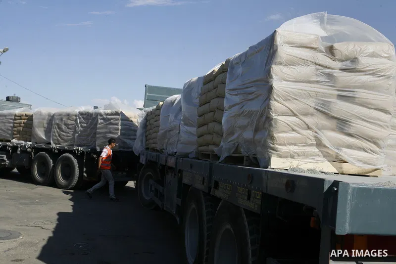 An employee walks past trucks loaded with bags of cement entering the Gaza Strip from Israel through the Kerem Shalom crossing, in Rafah in southern Gaza on October 14, 2014. International donors pledged about $5.4 billi...