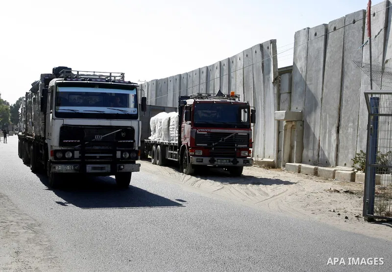 An employee walks past trucks loaded with bags of cement entering the Gaza Strip from Israel through the Kerem Shalom crossing, in Rafah in southern Gaza on October 14, 2014. International donors pledged about $5.4 billi...