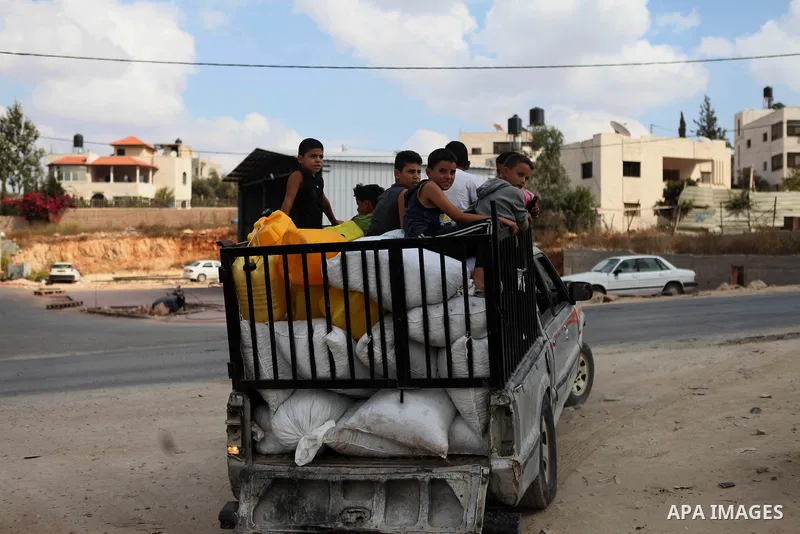 Palestinian children ride a car loaded with olive bags as they prepare to crush at a traditional stone press in the village of Deir Bzeigh near the West Bank city of Ramallah, 15 October 2014. Regional farmers are harves...