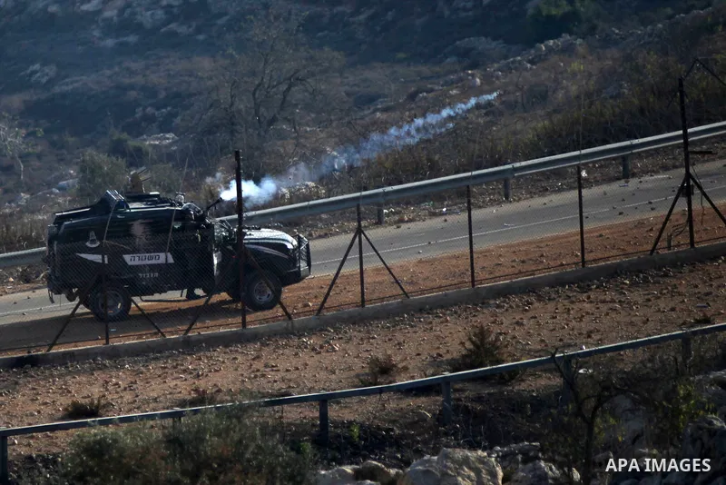 A member of Israeli security forces fires tear gas towards Palestinian protesters during clashes at a protest to show solidarity with al-Aqsa mosque, outside Israel's Ofer military prison near the West Bank city of Ramal...