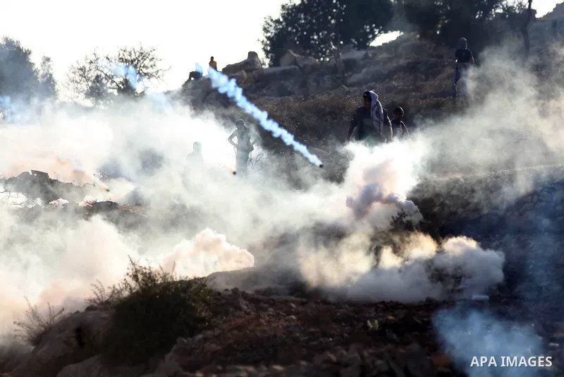 Palestinian protesters take cover from tear gas fired by Israeli security forces during clashes at a protest to show solidarity with al-Aqsa mosque, outside Israel's Ofer military prison near the West Bank city of Ramall...