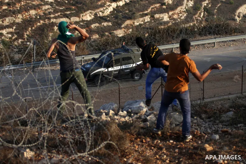 Palestinian protesters throw stones towards Israeli security forces during clashes at a protest to show solidarity with al-Aqsa mosque, outside Israel's Ofer military prison near the West Bank city of Ramallah October 17...