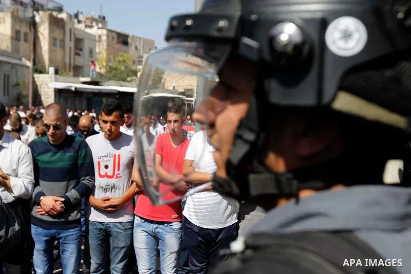 Israeli security forces stand guard as Palestinian Muslim worshipers perform traditional Friday prayers in a street outside the Old City in east Jerusalem on October 17, 2014. The Israeli government has restricted access...