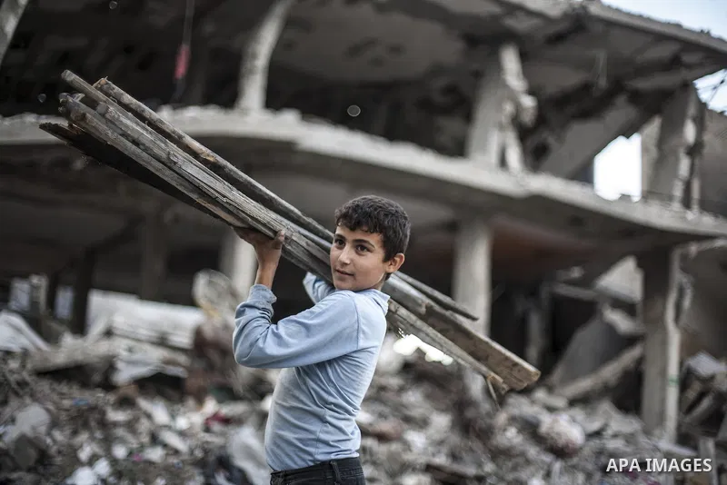 A member of a Palestinian family builds a shelter to protect them from winter rains, next to their destroyed house that witnesses said were destroyed during a seven-week Israeli offensive, on a rainy day in the town of B...