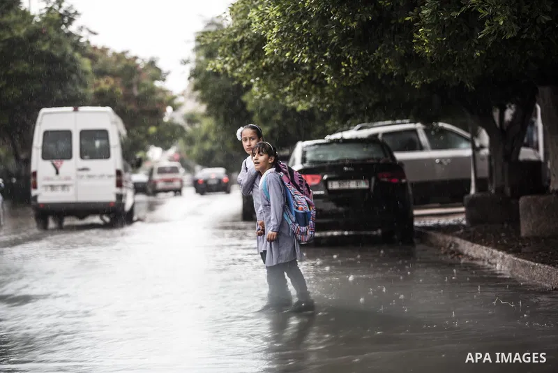 Palestinian students walk at a street, on a rainy day in Gaza City October 19, 2014. An open-ended ceasefire between Israel and Hamas-led Gaza militants, mediated by Egypt, took effect on August 26 after a seven-week con...