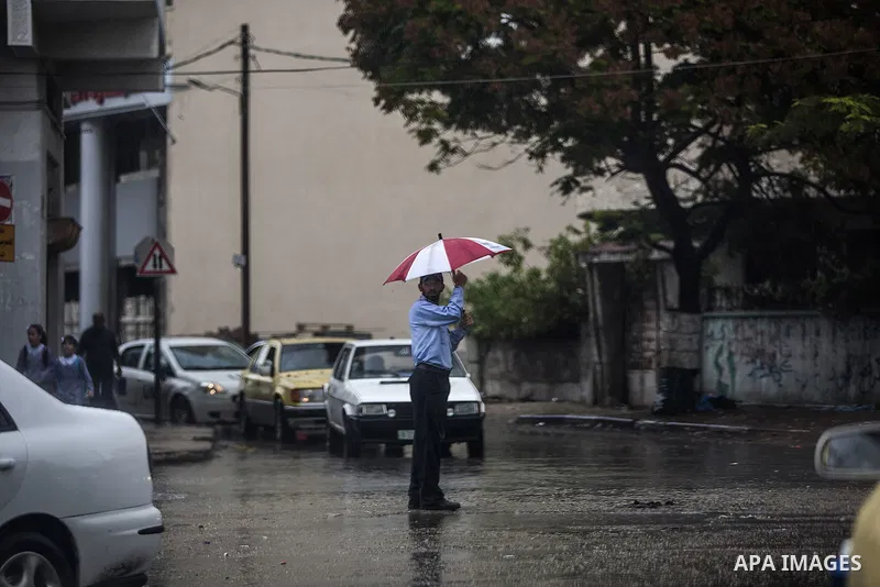 A Palestinian policeman holds an umbrella as he organizes the traffic at a street, on a rainy day in Gaza City October 19, 2014. An open-ended ceasefire between Israel and Hamas-led Gaza militants, mediated by Egypt, too...