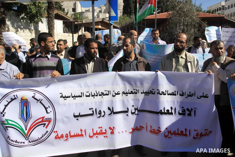 Palestinian employees of the former government in Gaza Strip hold banners during a protest to demanding their salaries, in front of the headquarters of the Council of Ministers in Gaza city, on October 21, 2014. Photo by...