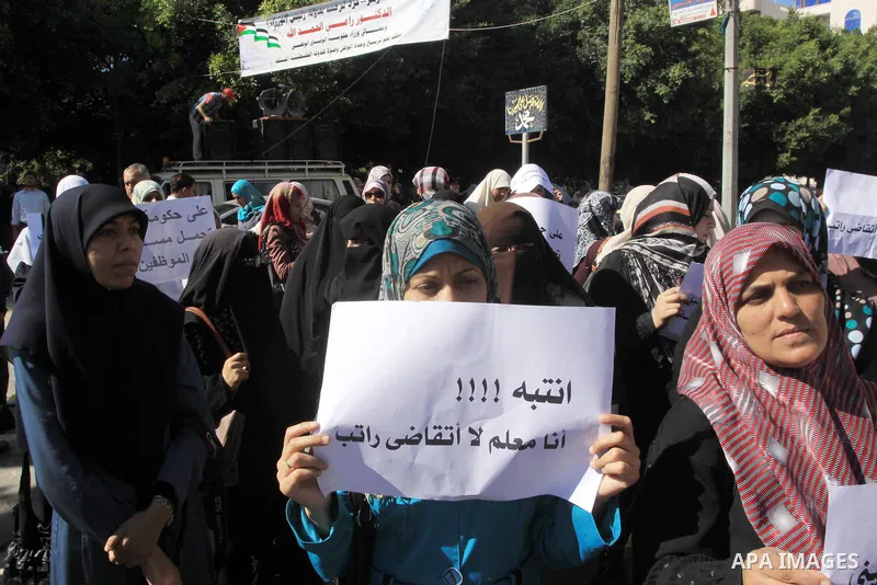 Palestinian employees of the former government in Gaza Strip hold banners during a protest to demanding their salaries, in front of the headquarters of the Council of Ministers in Gaza city, on October 21, 2014. Photo by...