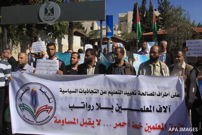 Palestinian employees of the former government in Gaza Strip hold banners during a protest to demanding their salaries, in front of the headquarters of the Council of Ministers in Gaza city, on October 21, 2014. Photo by...