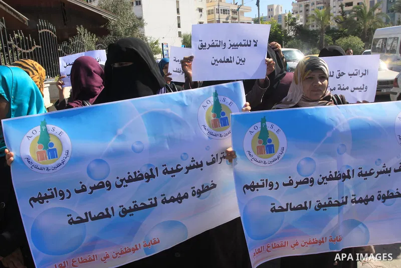 Palestinian employees of the former government in Gaza Strip hold banners during a protest to demanding their salaries, in front of the headquarters of the Council of Ministers in Gaza city, on October 21, 2014. Photo by...