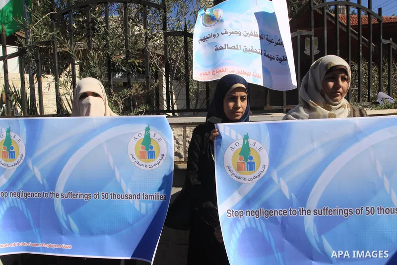 Palestinian employees of the former government in Gaza Strip hold banners during a protest to demanding their salaries, in front of the headquarters of the Council of Ministers in Gaza city, on October 21, 2014. Photo by...