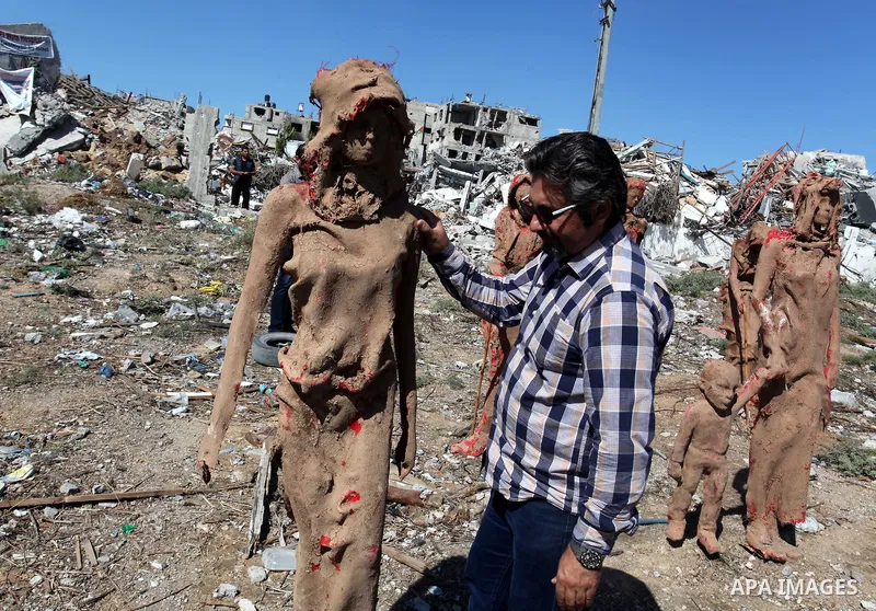 Palestinian artist Eyad Sabbah,40, adjusts a statue standing amidst the rubble of buildings destroyed during the 50 days of conflict between Israel and Hamas last summer, in the Shejaiya neighborhood of Gaza City on Octo...