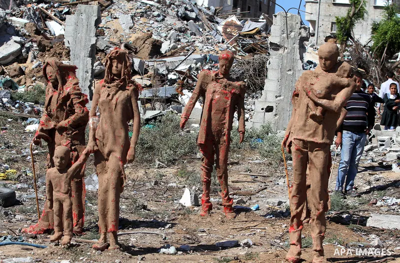 Palestinian srudents look at statues by Palestinian artist Eyad Sabbah,40, standing amidst the rubble of buildings destroyed during the 50 days of conflict between Israel and Hamas last summer, in the Shejaiya neighborho...