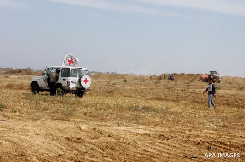 Palestinians stand near an International Committee of the Red Cross (ICRC) vehicle as the comittee assists Palestinian farmers to repair their fields that were devastated during the Israeli army summer's military offensi...