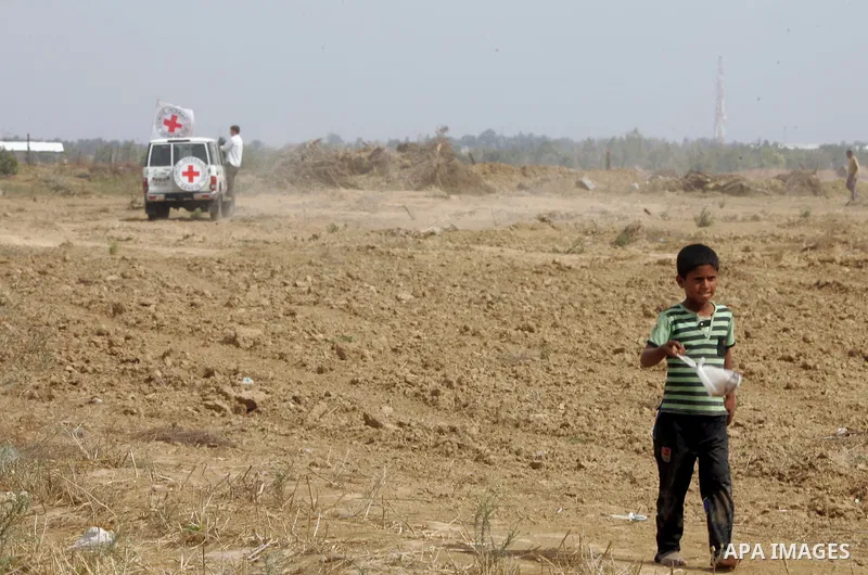 A Palestinian boy walks near an International Committee of the Red Cross (ICRC) vehicle as the comittee assists Palestinian farmers to repair their fields that were devastated during the Israeli army summer's military of...
