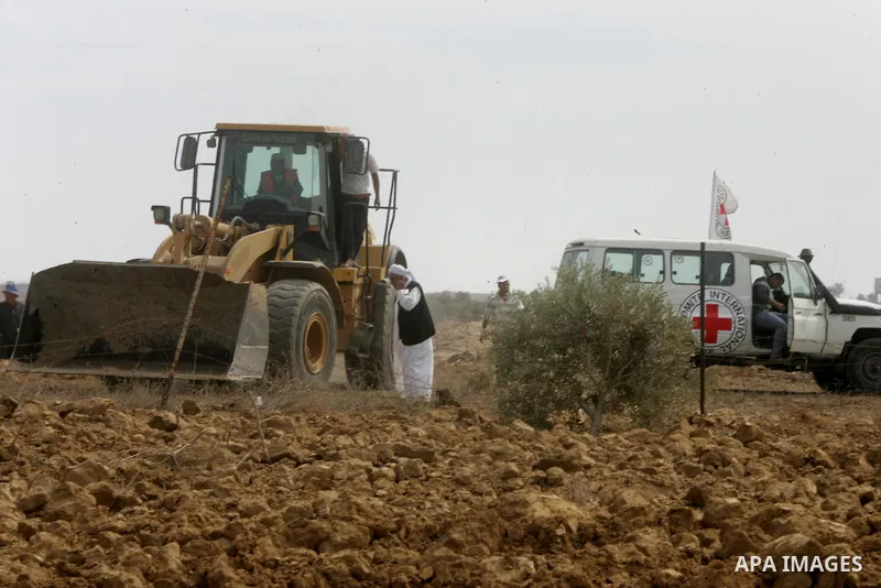 A Palestinian uses a digger in front of International Committee of the Red Cross (ICRC) workers as the comittee assists Palestinian farmers to repair their fields that were devastated during the Israeli army summer's mil...