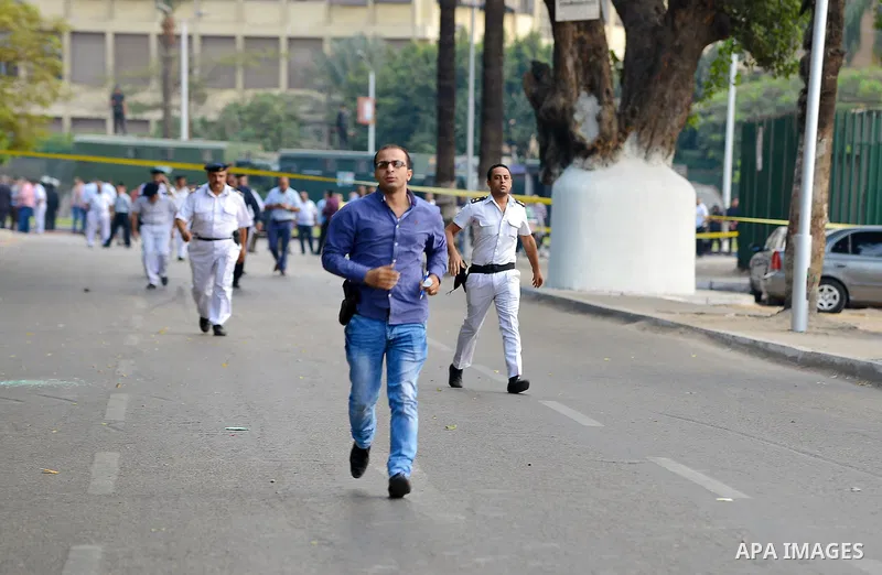 Egyptian policemen inspect the site where a bomb exploded outside the main gate of Cairo University on October 22, 2014, wounding at least nine people including a senior officer. The assistant police chief of Cairo's Giz...