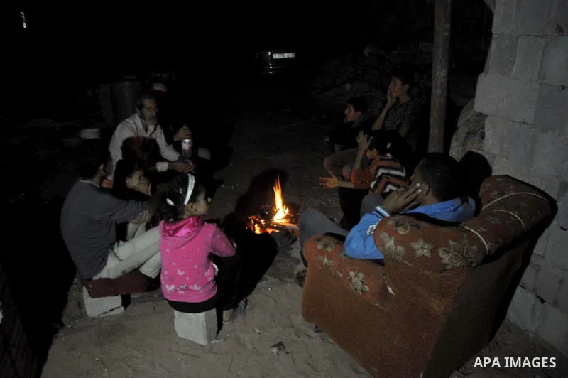 Palestinians warm themselves around a fire, at their destroyed house in al-Shejaiya neighbourhood in the east of Gaza City, October 23, 2014. With the cold days of winter approaching, more than 100,000 Gaza residents are...