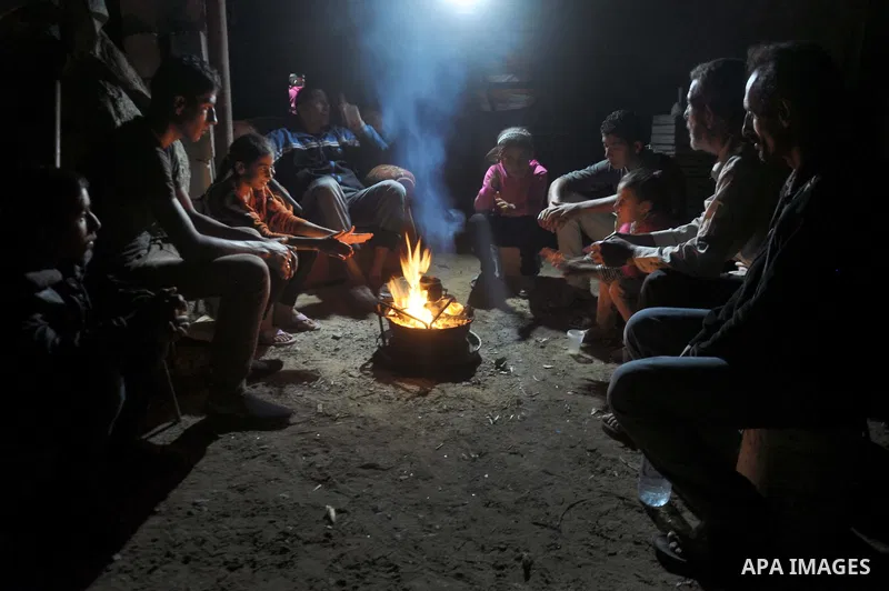 Palestinians warm themselves around a fire, at their destroyed house in al-Shejaiya neighbourhood in the east of Gaza City, October 23, 2014. With the cold days of winter approaching, more than 100,000 Gaza residents are...