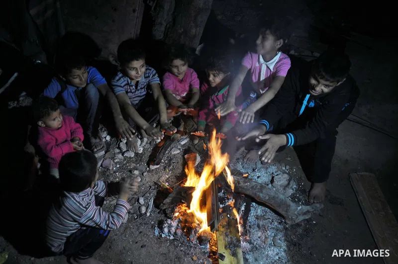 Palestinians warm themselves around a fire, at their destroyed house in al-Shejaiya neighbourhood in the east of Gaza City, October 23, 2014. With the cold days of winter approaching, more than 100,000 Gaza residents are...