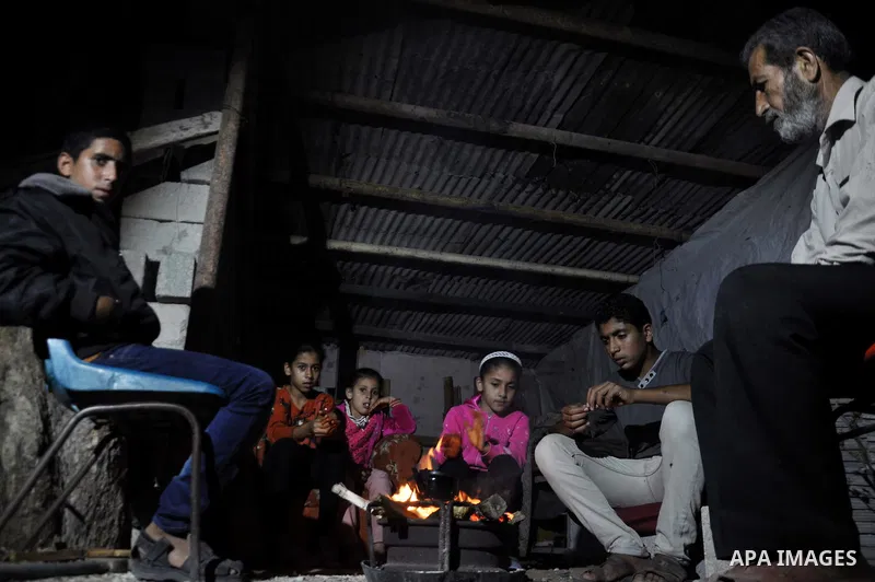 Palestinians warm themselves around a fire, at their destroyed house in al-Shejaiya neighbourhood in the east of Gaza City, October 23, 2014. With the cold days of winter approaching, more than 100,000 Gaza residents are...