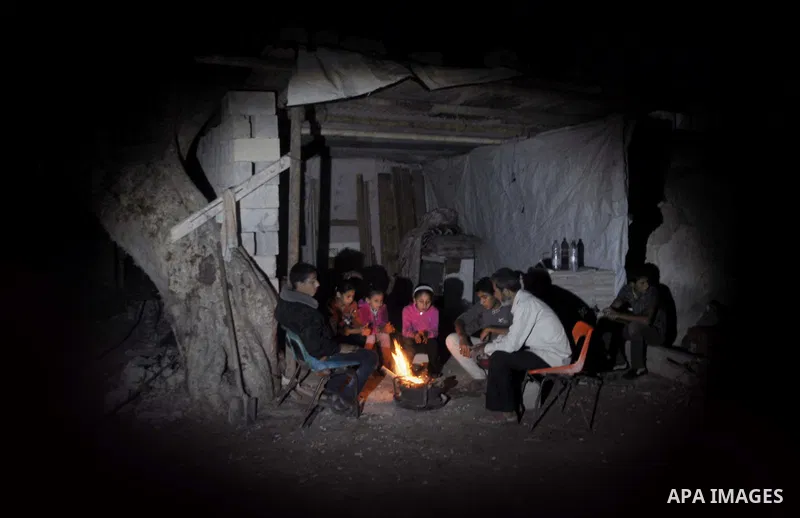 Palestinians warm themselves around a fire, at their destroyed house in al-Shejaiya neighbourhood in the east of Gaza City, October 23, 2014. With the cold days of winter approaching, more than 100,000 Gaza residents are...