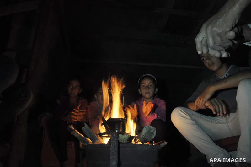 Palestinians warm themselves around a fire, at their destroyed house in al-Shejaiya neighbourhood in the east of Gaza City, October 23, 2014. With the cold days of winter approaching, more than 100,000 Gaza residents are...