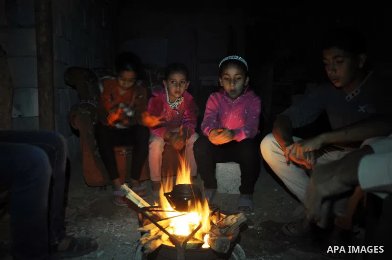 Palestinians warm themselves around a fire, at their destroyed house in al-Shejaiya neighbourhood in the east of Gaza City, October 23, 2014. With the cold days of winter approaching, more than 100,000 Gaza residents are...