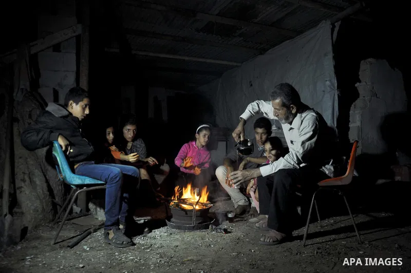 Palestinians warm themselves around a fire, at their destroyed house in al-Shejaiya neighbourhood in the east of Gaza City, October 23, 2014. With the cold days of winter approaching, more than 100,000 Gaza residents are...