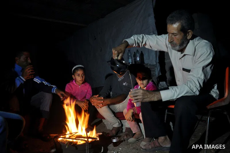 Palestinians warm themselves around a fire, at their destroyed house in al-Shejaiya neighbourhood in the east of Gaza City, October 23, 2014. With the cold days of winter approaching, more than 100,000 Gaza residents are...
