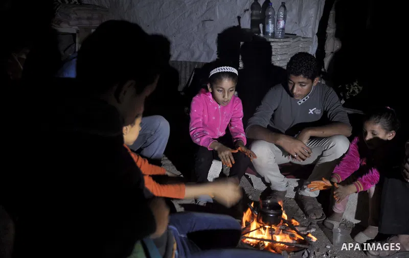 Palestinians warm themselves around a fire, at their destroyed house in al-Shejaiya neighbourhood in the east of Gaza City, October 23, 2014. With the cold days of winter approaching, more than 100,000 Gaza residents are...