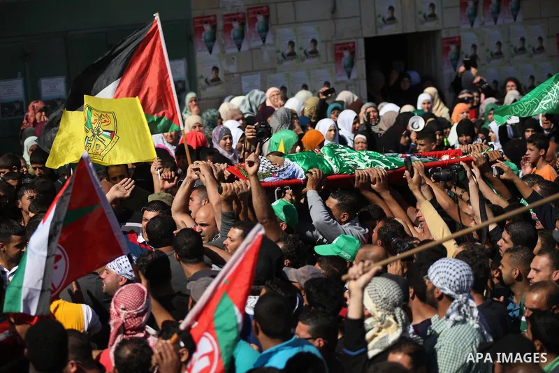 Mourners carry the body of Palestinian-American youth Orwah Hammad, whom medics said was killed by Israeli forces, during his funeral in the West Bank village of Silwad near Ramallah October 26, 2014. Israeli forces shot...