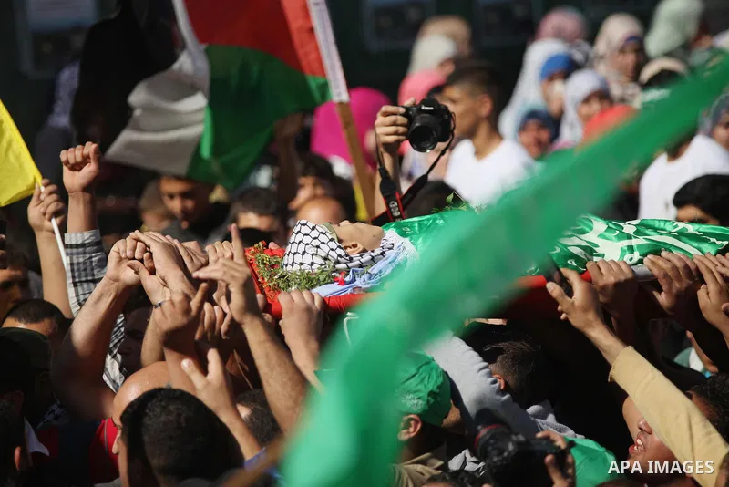 Mourners carry the body of Palestinian-American youth Orwah Hammad, whom medics said was killed by Israeli forces, during his funeral in the West Bank village of Silwad near Ramallah October 26, 2014. Israeli forces shot...