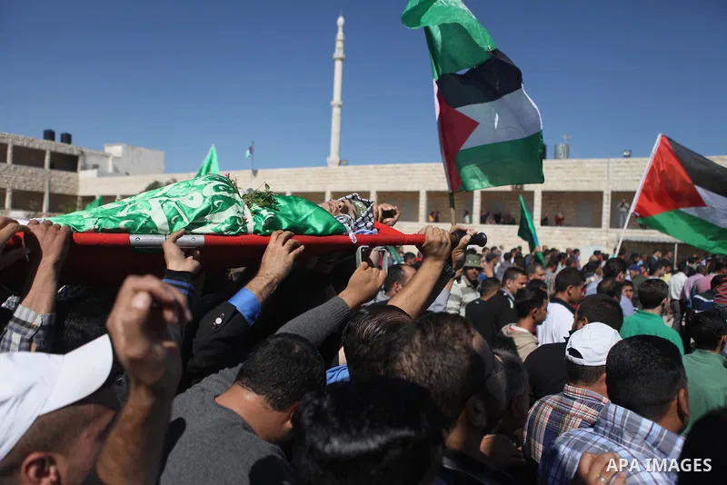 Mourners carry the body of Palestinian-American youth Orwah Hammad, whom medics said was killed by Israeli forces, during his funeral in the West Bank village of Silwad near Ramallah October 26, 2014. Israeli forces shot...