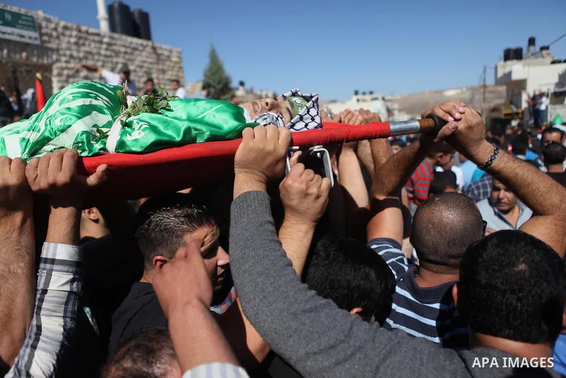 Mourners carry the body of Palestinian-American youth Orwah Hammad, whom medics said was killed by Israeli forces, during his funeral in the West Bank village of Silwad near Ramallah October 26, 2014. Israeli forces shot...
