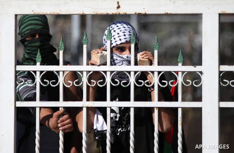 Palestinian youths look on behind a shelter during clashes with Israeli security forces after funeral Palestinian-American, Orwah Hammad, 14, who was shot dead last Friday during clashes with Israeli army soldiers, at th...