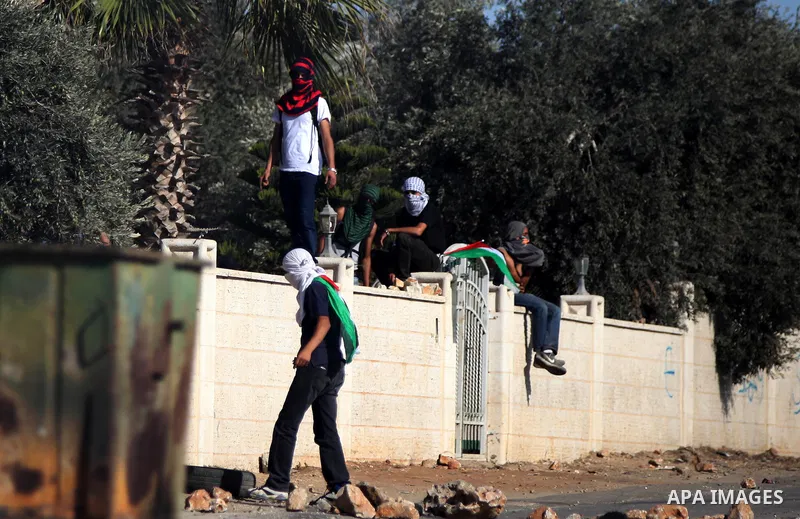 Palestinian youths look on during clashes with Israeli security forces after funeral Palestinian-American, Orwah Hammad, 14, who was shot dead last Friday during clashes with Israeli army soldiers, at the entrance of Ham...