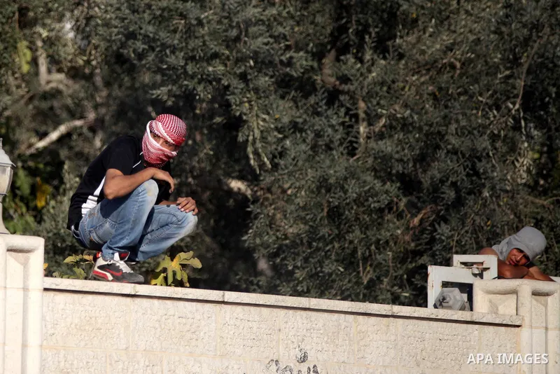 Palestinian youths look on during clashes with Israeli security forces after funeral Palestinian-American, Orwah Hammad, 14, who was shot dead last Friday during clashes with Israeli army soldiers, at the entrance of Ham...