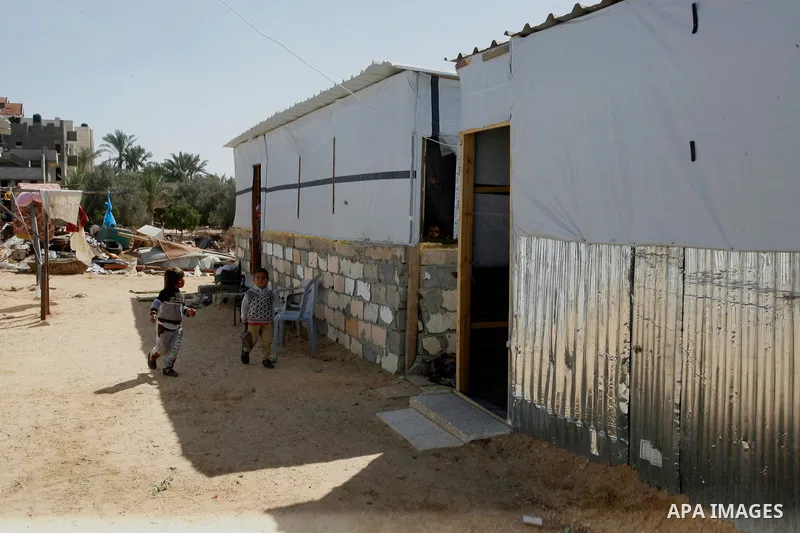 Palestinian children play outside their containers donated by a charity organisation as temporary housing for those whose houses were destroyed during a seven-week Israeli offensive, in Khuzaa, east of Khan Younis, in th...