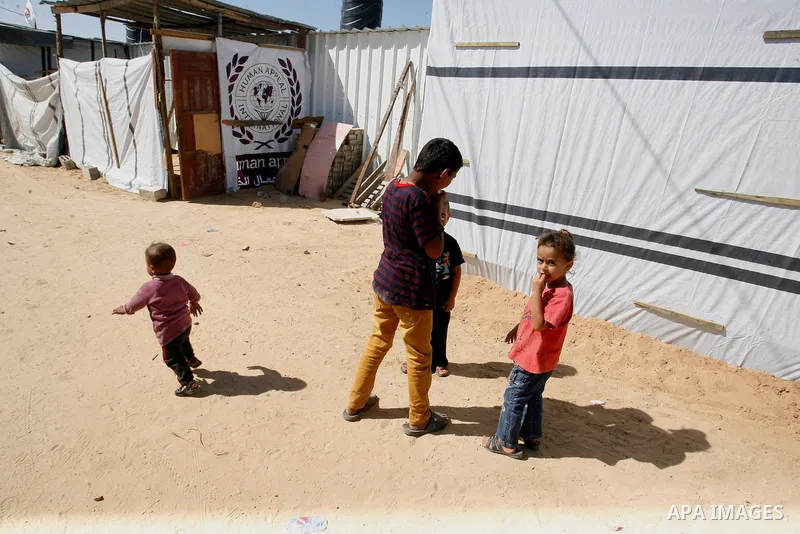 Palestinian children play outside their containers donated by a charity organisation as temporary housing for those whose houses were destroyed during a seven-week Israeli offensive, in Khuzaa, east of Khan Younis, in th...