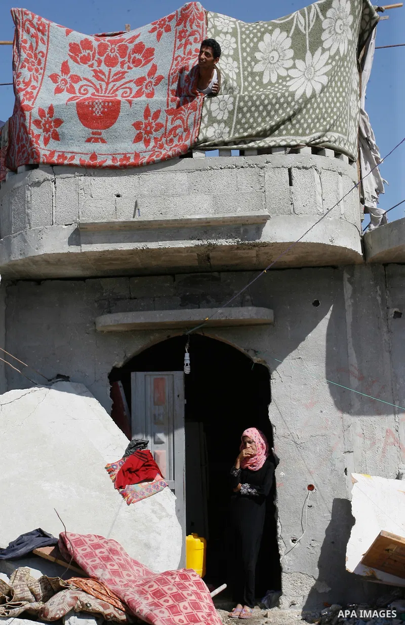 A Palestinian woman removes her belongings amongst the rubble of house which witnesses said was destroyed by Israeli forces during the most recent conflict between Israel and Hamas, in Khuzaa in the east of Khan Younis,...