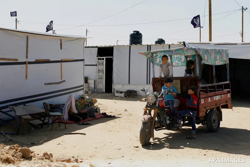Palestinian families sit outside their containers donated by a charity organisation as temporary housing for those whose houses were destroyed during a seven-week Israeli offensive, in Khuzaa, east of Khan Younis, in the...