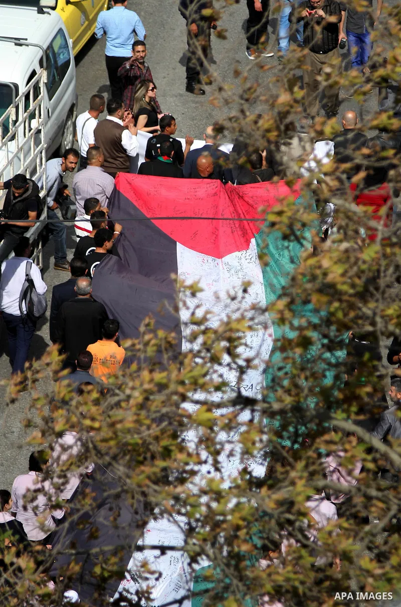 People march as they hold a large Palestinian flag during an attempt to break the Guinness World Record for the "largest Palestinian flag", in the West Bank city of Ramallah October 28, 2014. Photo by Shadi Hatem