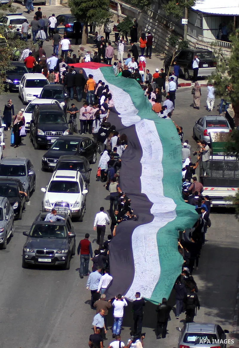 People march as they hold a large Palestinian flag during an attempt to break the Guinness World Record for the "largest Palestinian flag", in the West Bank city of Ramallah October 28, 2014. Photo by Shadi Hatem