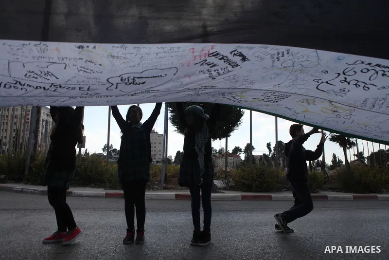 People march as they hold a large Palestinian flag during an attempt to break the Guinness World Record for the "largest Palestinian flag", in the West Bank city of Ramallah October 28, 2014. Photo by Shadi Hatem