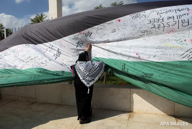 People march as they hold a large Palestinian flag during an attempt to break the Guinness World Record for the "largest Palestinian flag", in the West Bank city of Ramallah October 28, 2014. Photo by Shadi Hatem