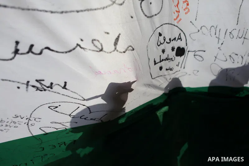 A man writes on a Palestinian flag during an attempt to break the Guinness World Record for the "largest Palestinian flag", in the West Bank city of Ramallah October 28, 2014. Photo by Shadi Hatem