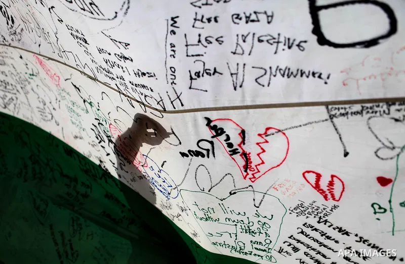 A man writes on a Palestinian flag during an attempt to break the Guinness World Record for the "largest Palestinian flag", in the West Bank city of Ramallah October 28, 2014. Photo by Shadi Hatem