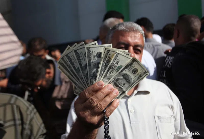 A Palestinian employee of the former Hamas government holds 1,200 US dollars in cash outside a post office in Gaza City on October 29, 2014 after receiving part of his wages that has been delayed for months. The Palestin...
